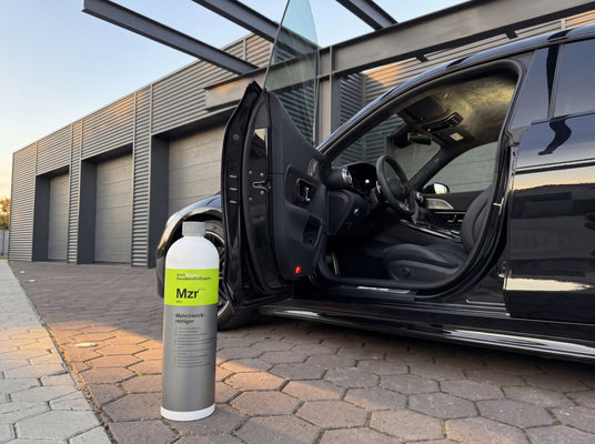 Koch-Chemie Mzr 1L Flasche neben offener Tür eines schwarzen Mercedes-AMG GT in der Warehouse-Werkstatt