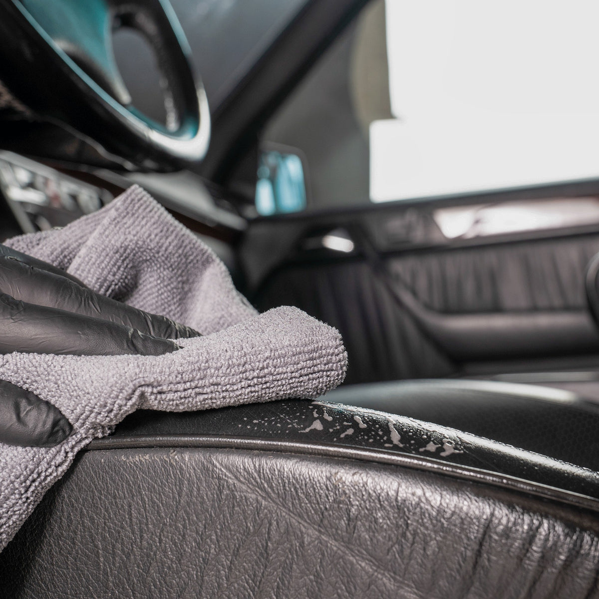 detiiling1.comLOURLOCK Leather Cleaner (Mild) — wiping down a black leather seat bolster with a microfibre towel
