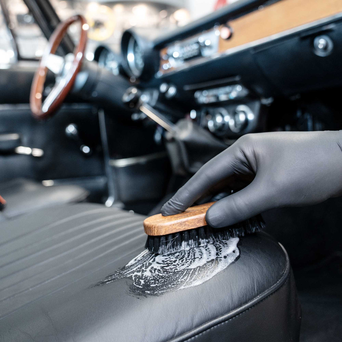 detiiling1.comLOURLOCK classic car leather care — brushing a classic car's leather seat with foam